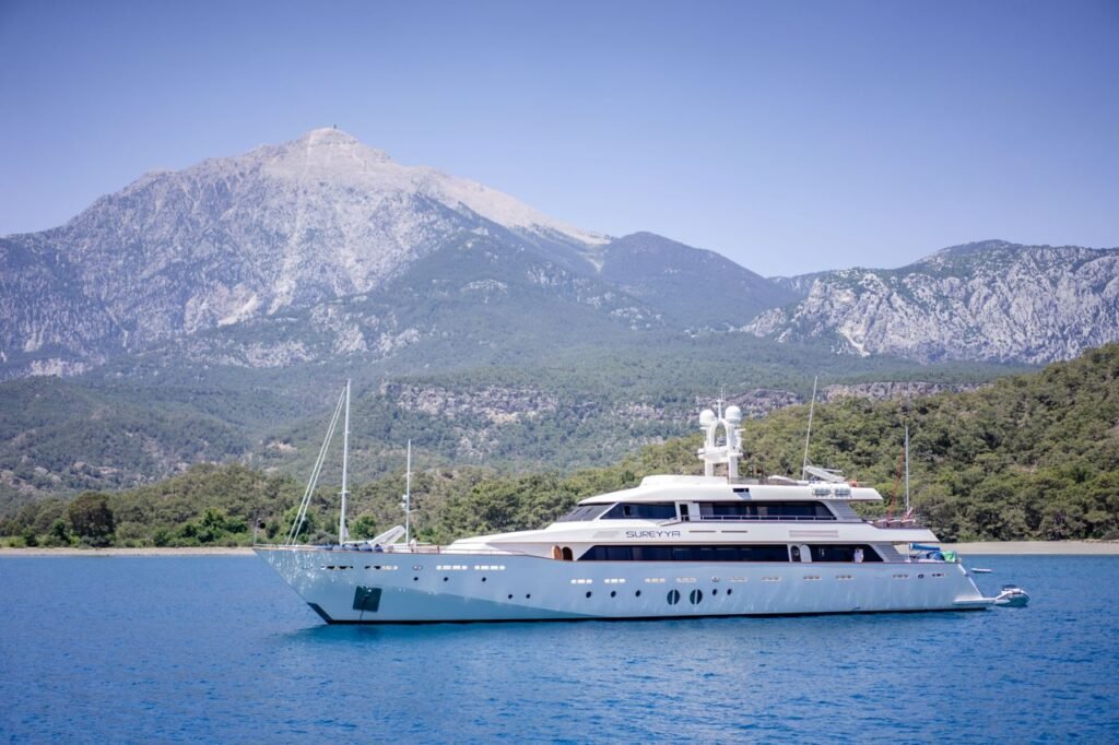 A sleek yacht sailing in front of majestic mountains in Kemer, Antalya, Turkey.