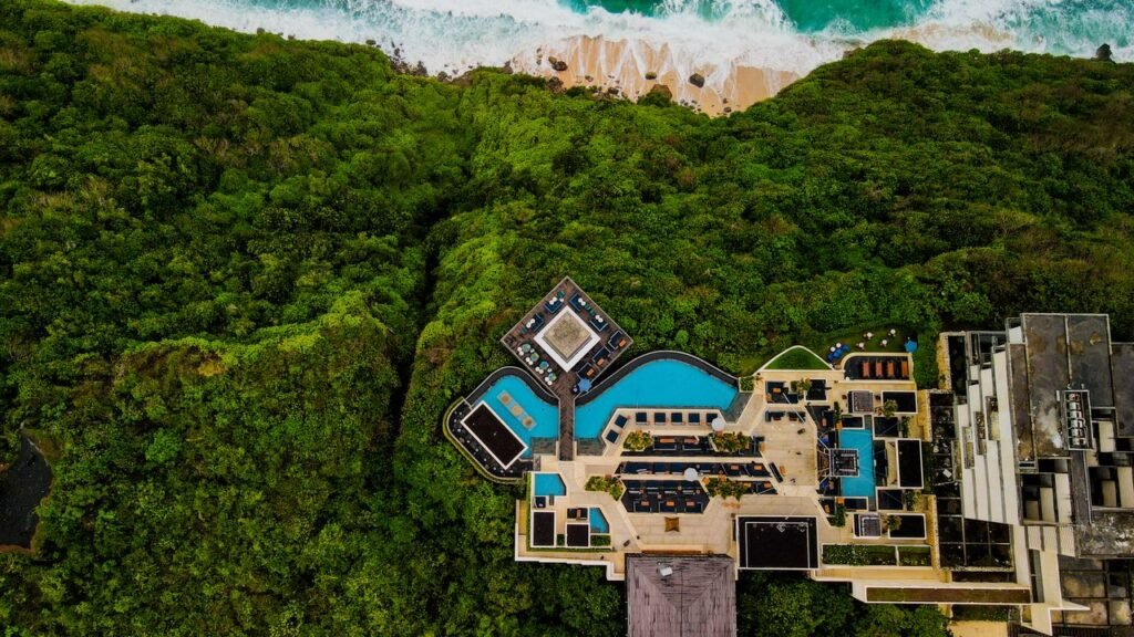 Stunning aerial shot of a luxury resort in Bali, surrounded by lush greenery and ocean view.