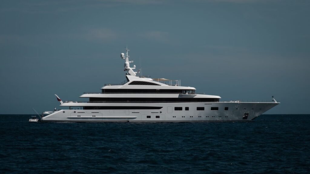A sleek luxury yacht cruising on the calm open ocean under a clear sky.