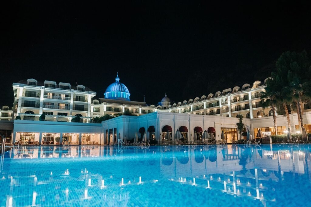 A luxurious hotel with a blue lit swimming pool and dome, captured during nighttime.